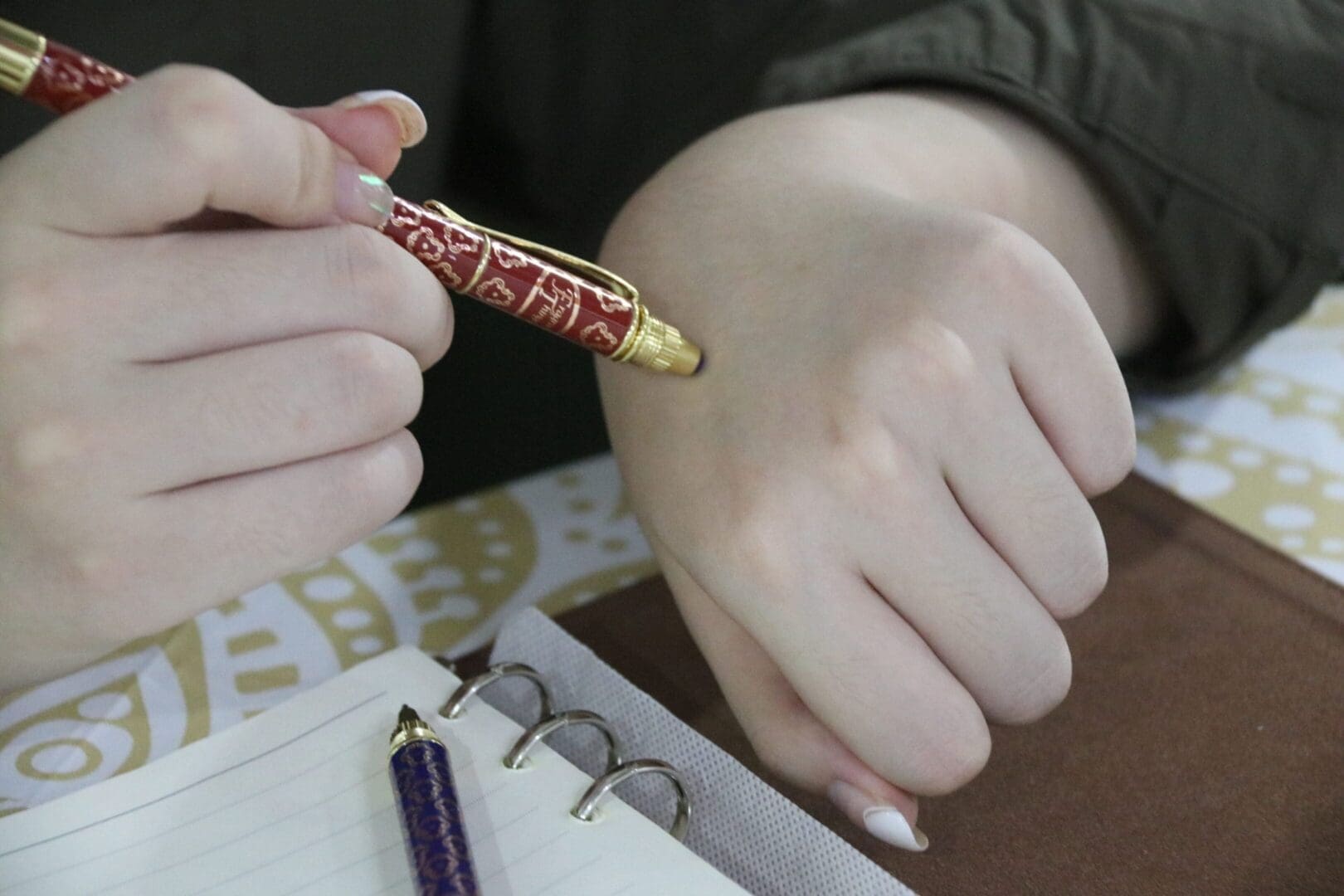 Hand holding pen over notebook, writing notes.